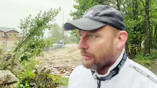 Man wearing a white jacket and grey baseball cap.