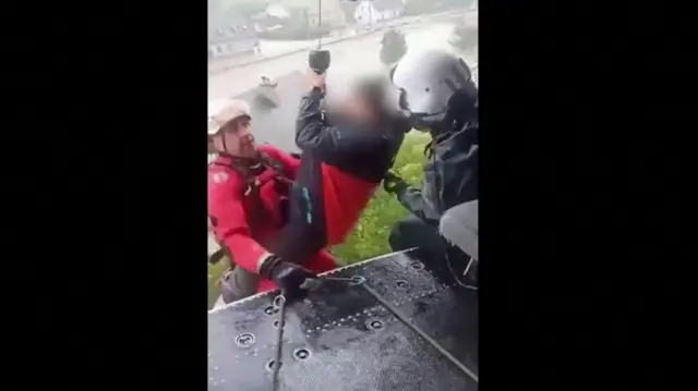 Person being winched into a helicopter