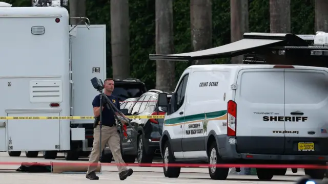 A law enforcement officer walks near emergency service vehicles