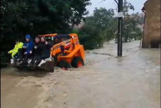 People ride in the bucket of a small digger driving in flood water in Lipov in south Moravia region