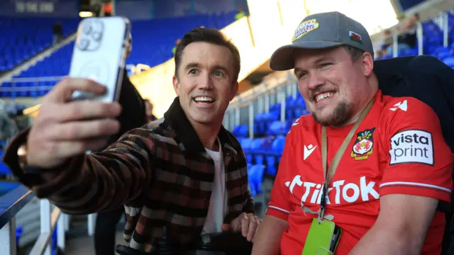 Wrexham co-owner Rob McElhenny poses for a photo with a fan