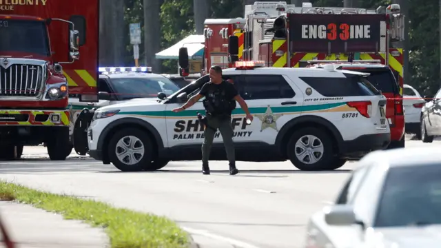 A police officer gestures in the road in front of Sheriff car and fire engine