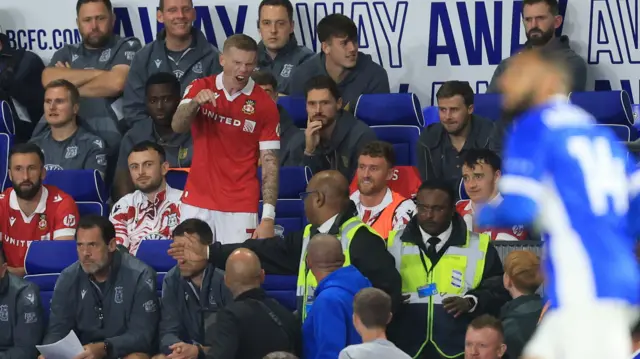 Wrexham's James McClean appears to be arguing with Birmingham City fans as he takes his seat on the bench after being substituted.