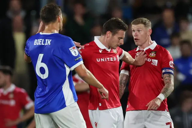 Wrexham's James McClean gestures at Birmingham City's Krystian Bielik as the two players are held apart.