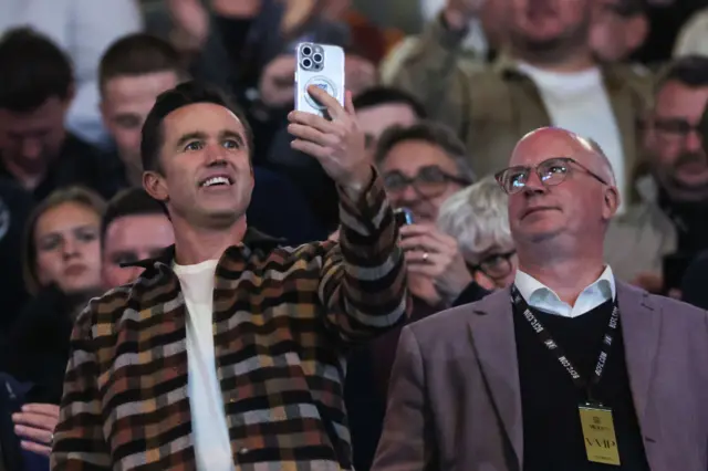 Rob McElhenney, co owner of Wrexham hold up Ryan Reynolds, co owner of Wrexham on his mobile phone