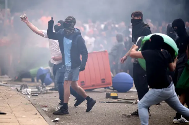 Masked people throw furniture and rocks at hotel