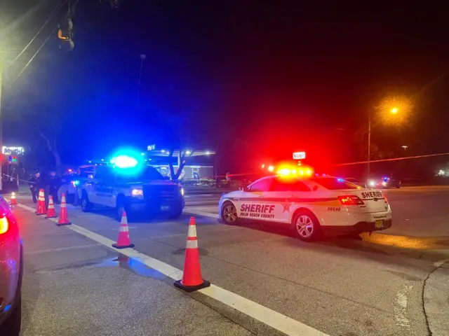 Multiple police car with their lights on, alongside traffic cones