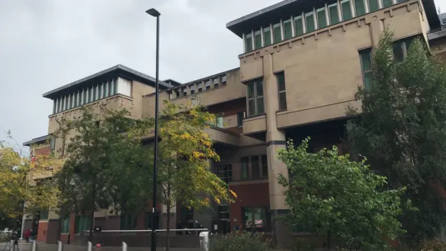 Blocky large building partially obscured by trees