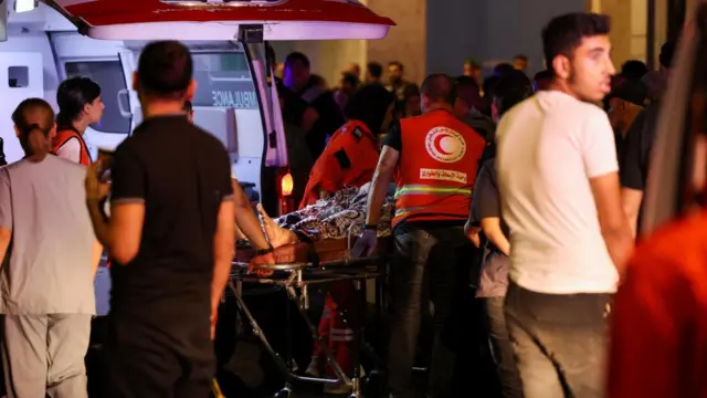 An injured person is wheeled on a stretcher out of a Red Crescent van