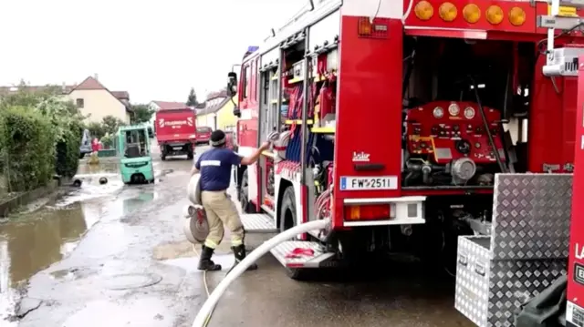 Firefighter pulling a hose out of a firetruck during clean-up operation in Austrian town