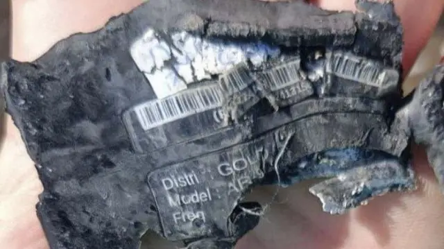 The remnants of a barcode on a mangled piece of black plastic