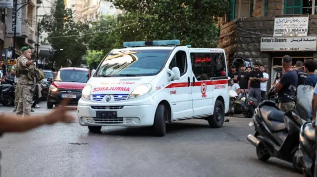 An ambulance arrives to American University of Beirut Medical Center, soliders are directing it as people watch on the streets