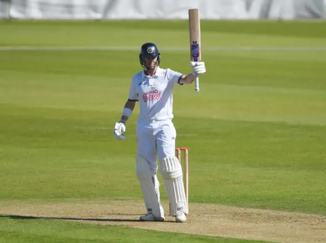 Nick Gubbins waves his bat after scoring 50