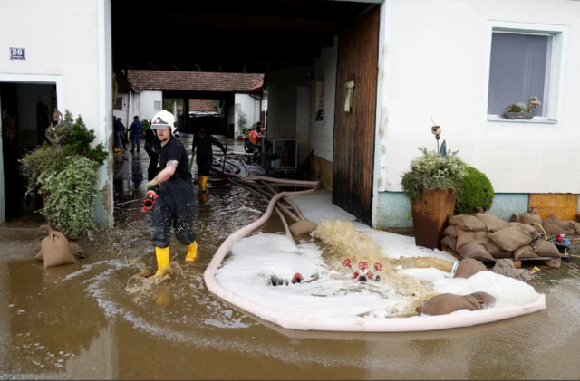 Residents and firefighters clean up a house, following heavy rainfall which caused flooding