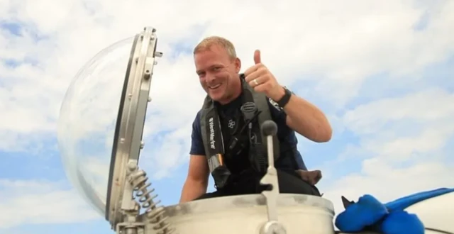 A man with blonde hair giving a thumbs up sign