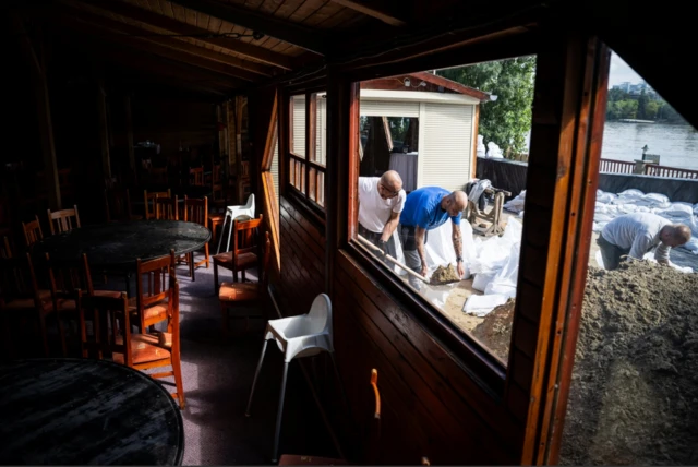 People fill sandbags next to a restaurant on the banks of the Danube