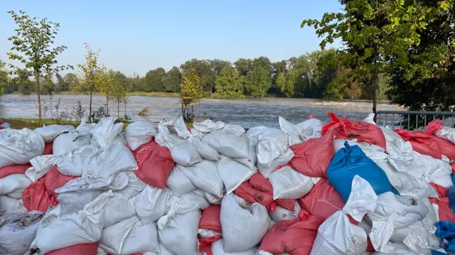 Red and white sandbags piled up against a river