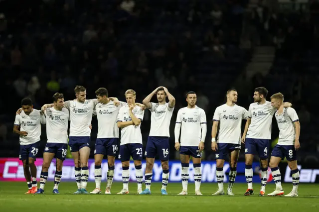 Preston players nervously wait for the next penalty