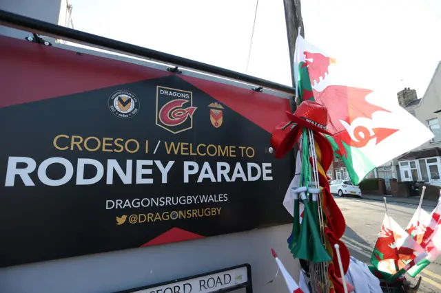 Wales flags in front of Welcome to Rodney Parade sign