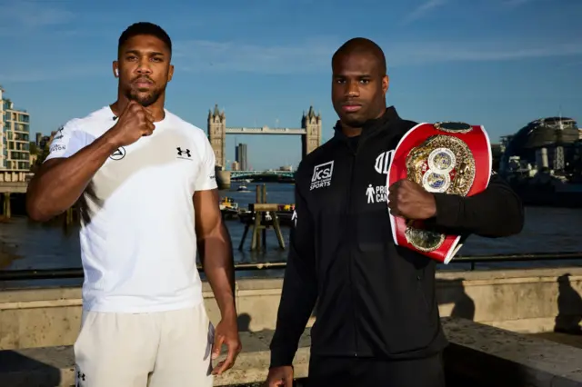 Anthony Joshua holds up his fist as he stands next to Daniel Dubois, who has the IBF heavyweight title on his shoulder