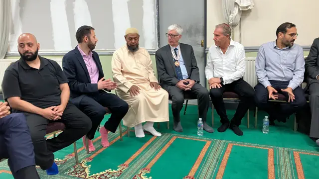 Men sitting around on chairs in a mosque