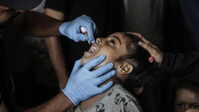 A nurse administers polio vaccine drops to a Palestinian child