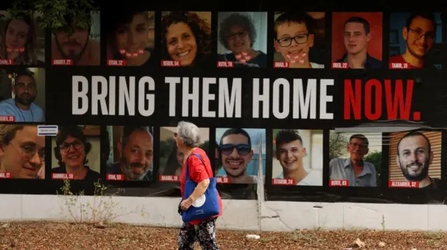 A woman walks past posters of hostages believed to be in Gaza