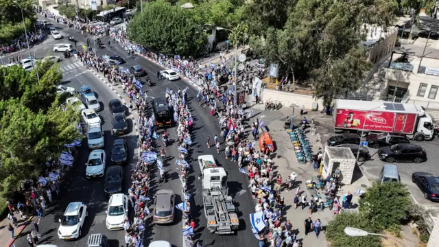 Drone photo showing people lining streets waving Israeli flags as cars drive past