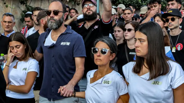 Hersh's family hold hands with each other while standing in a procession of people