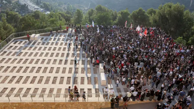 An aerial picture showing a crowd gathering in one half of a graveyard