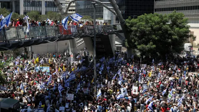 Taken from afar, a crowd holds Israeli flags and various posters