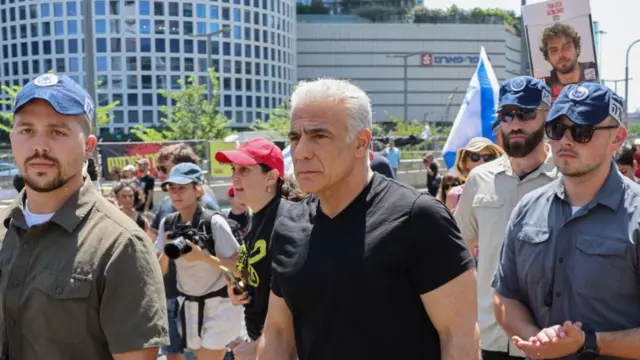 Lapid walks among protesters down a street