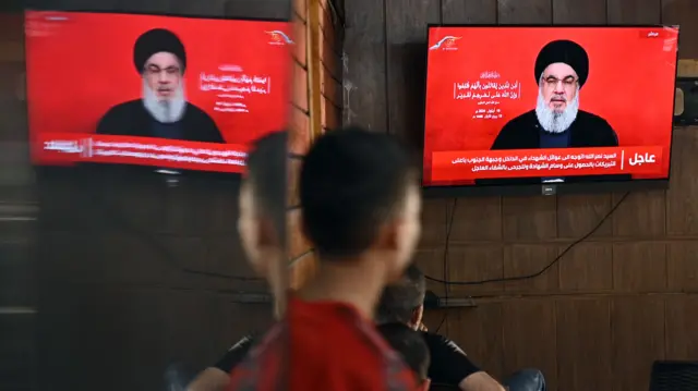 People watch Hezbollah Secretary-General Hassan Nasrallah delivering a televised speech at a coffee shop in Beirut on Thursday