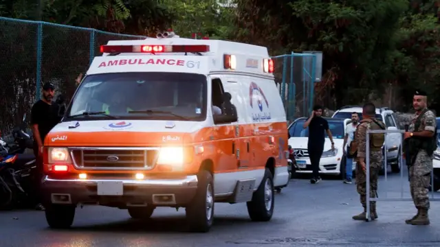 An ambulance arrives outside a hospital as members of the Lebanese military stand nearby