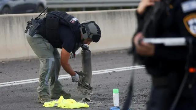 An Israeli police officer handles part of a rocket