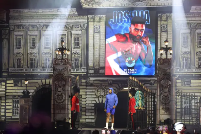 Anthony Joshua enters the open workouts flanked by king's guard