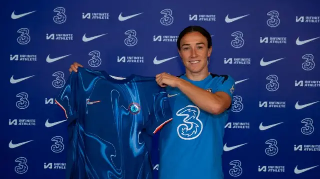 Lucy Bronze holding a Chelsea shirt