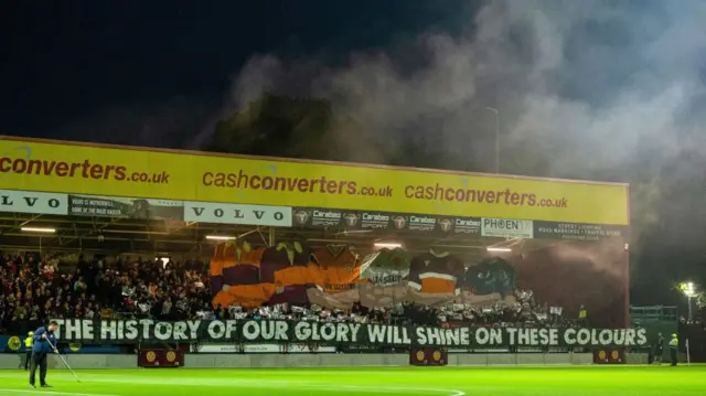 MOTHERWELL, SCOTLAND - SEPTEMBER 20: Motherwell fans hold up a display which reads 'The history of our glory will shine on these colours' during a Premier Sports Cup quarter-final match between Motherwell and Dundee United at Fir Park, on September 20, 2024, in Motherwell, Scotland. (Photo by Craig Foy / SNS Group)