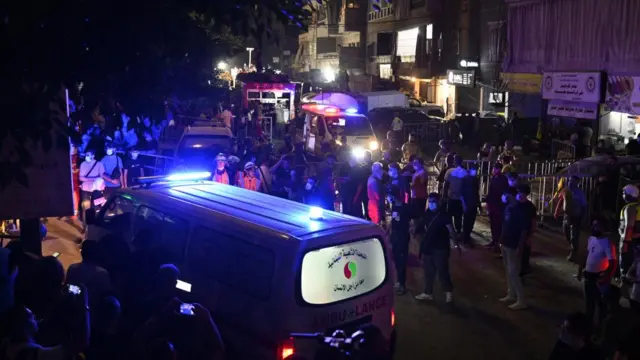 Ambulance on streets of Beirut as people crowd around as night falls