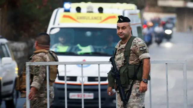 Members of Lebanese military stand in front of gate as Ambulance appears in background