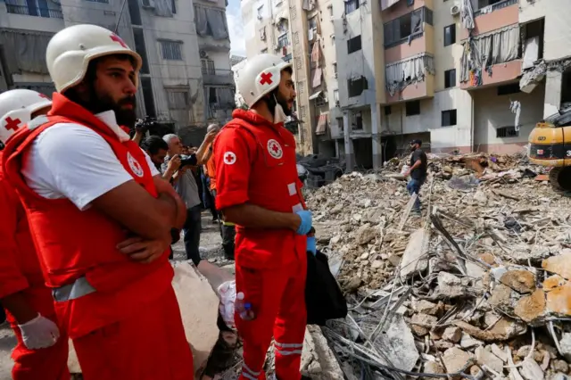 Several medical staff in Red Cross uniforms stand at the site of an Israeli strike on a Beirut suburb on 20 Friday