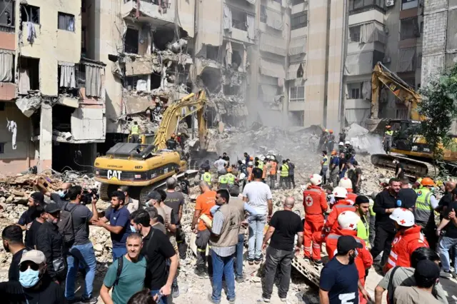 Medical workers at the site of an Israeli strike on a Beirut suburb on 20 Friday with severely damaged buildings and two excavators seen clearing the debris