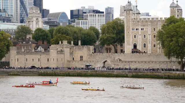 Five boats going along the Thames against the Tower of London