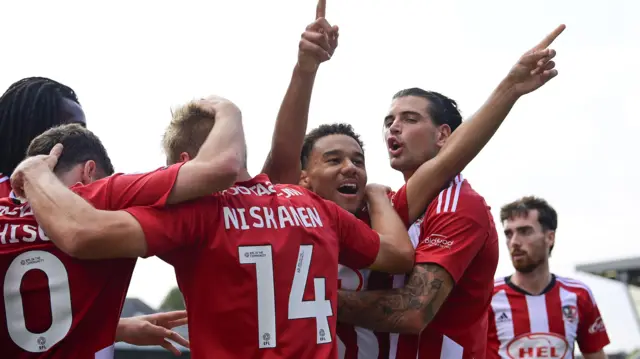 Exeter players mob Kami Doyle after his goal against Stevenage.