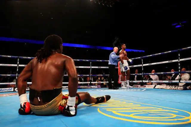 Charles Martin is on his bum on the canvas as Anthony Joshua is held by the referee