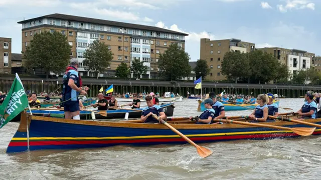 A group of women in a long blue, yellow and red boat