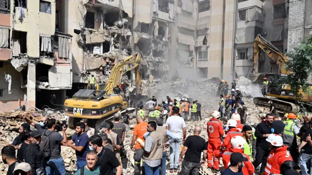 Emergency workers use excavators to clear the rubble at the site which was targeted by an Israeli strike on Friday