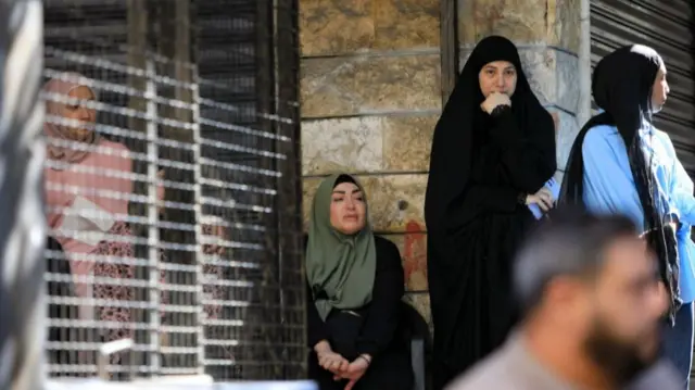 Women react as they wait at the scene of an Israeli strike that targeted a Beirut southern suburb