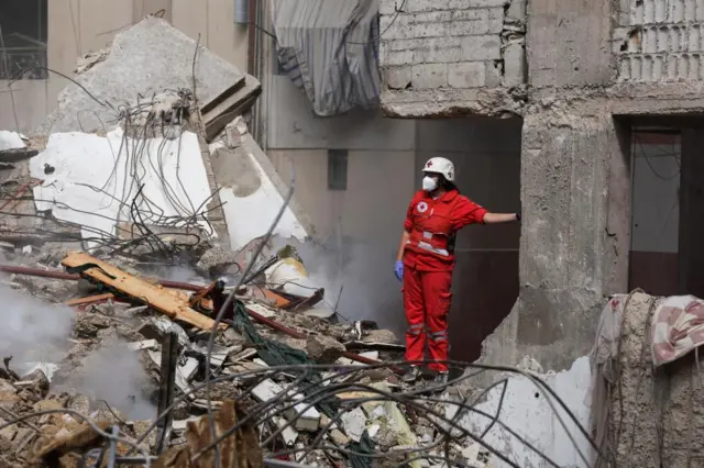 A RedCross medical worker standing amid the rubble of damaged buildings at the site of an Israeli strike on a Beirut suburb on 20 Friday