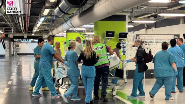 Hospital staff wheel patients in bed into a parking garage